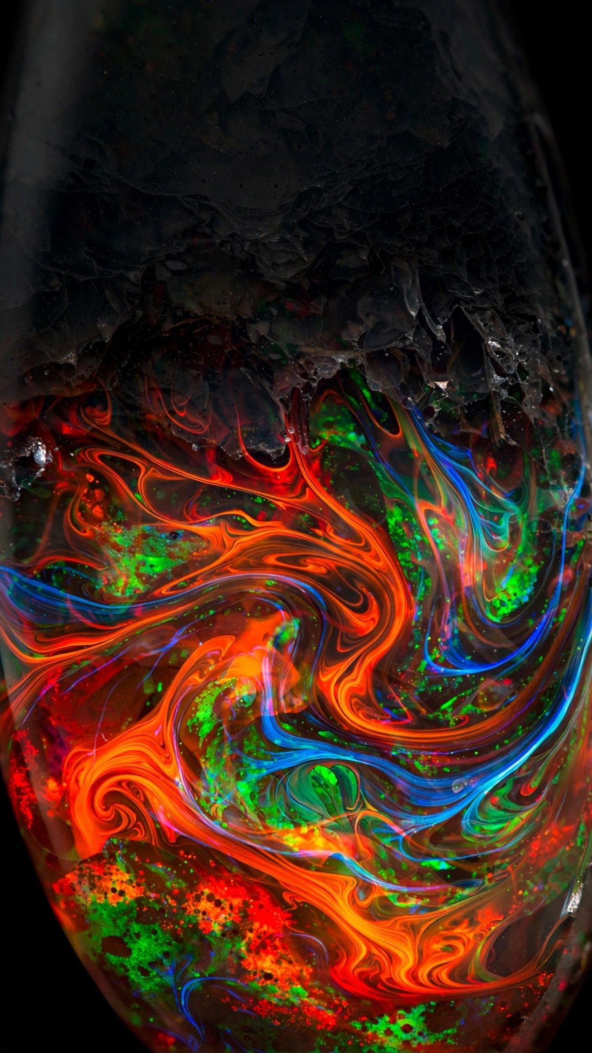 Macro of fire opal gemstone with swirling play-of-color flames in orange red green and blue, abstract wallpaper