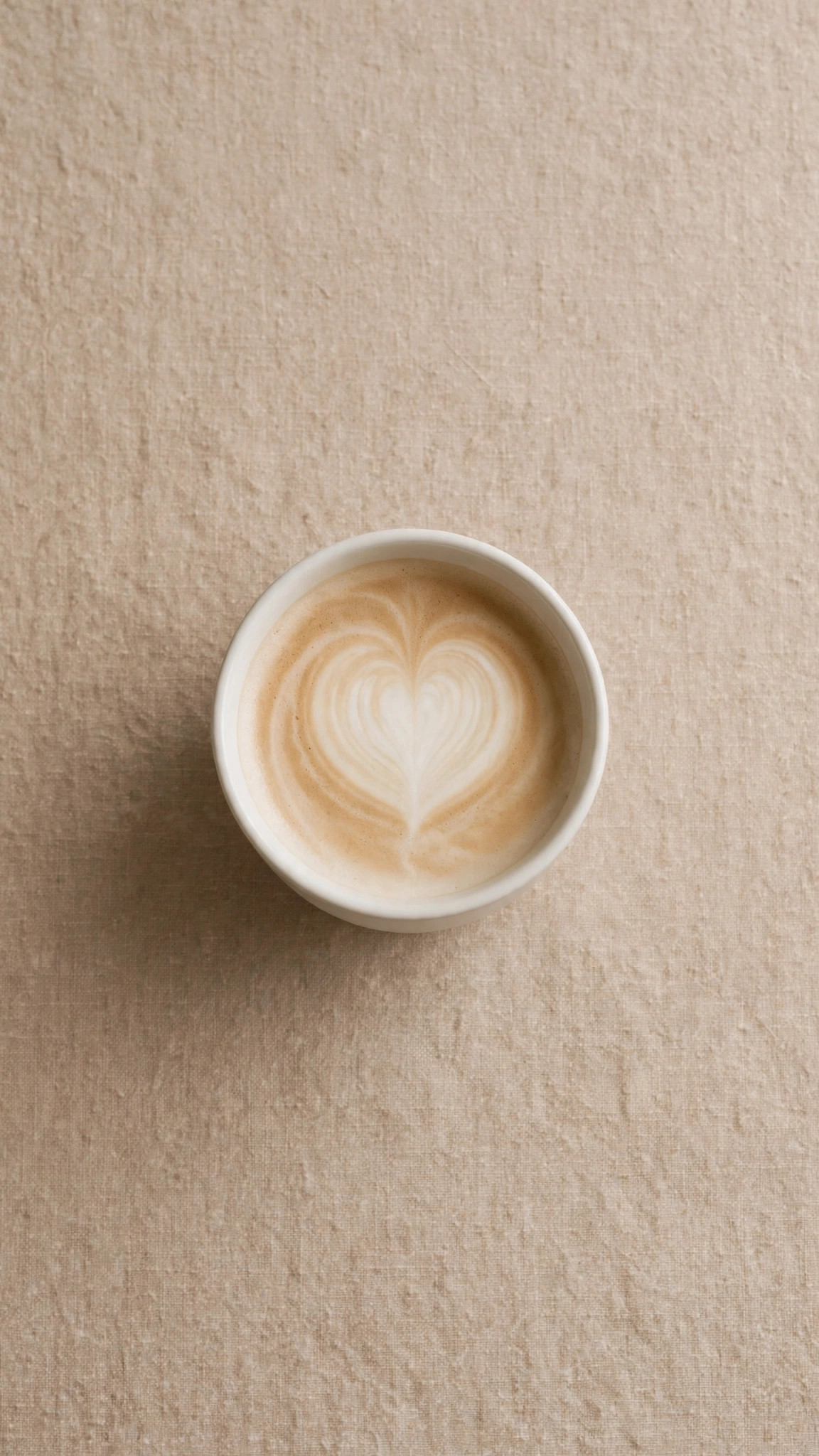 Single white coffee cup seen from directly above on a warm beige table