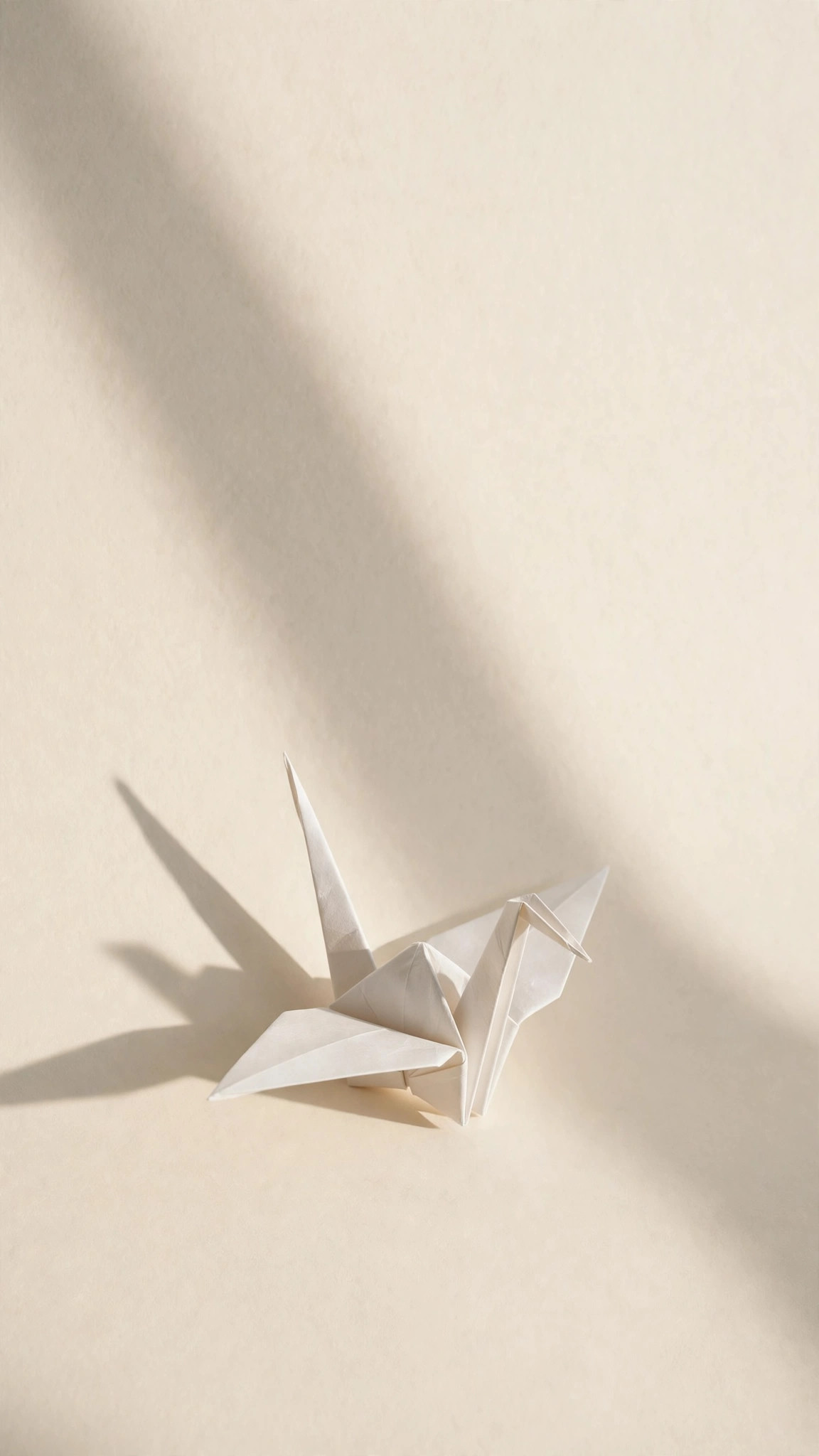 Single white paper origami crane casting a soft long shadow on a cream background