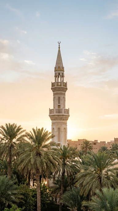 A slender minaret rising above palm trees.