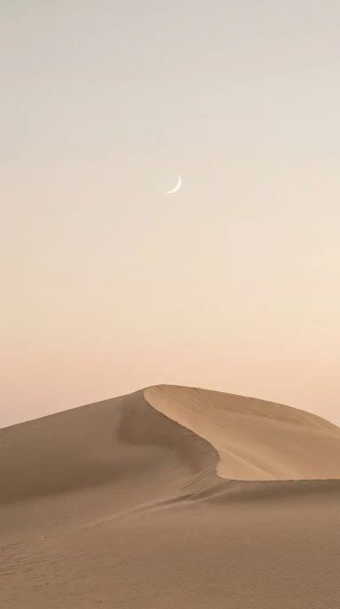 A small crescent above a sand dune.