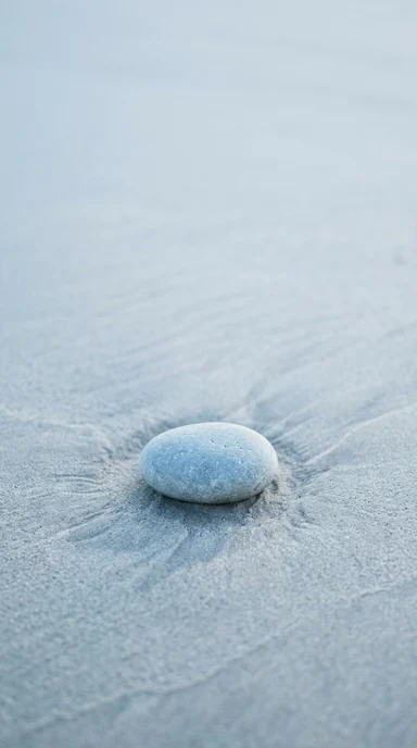 A smooth stone on rippled sand.